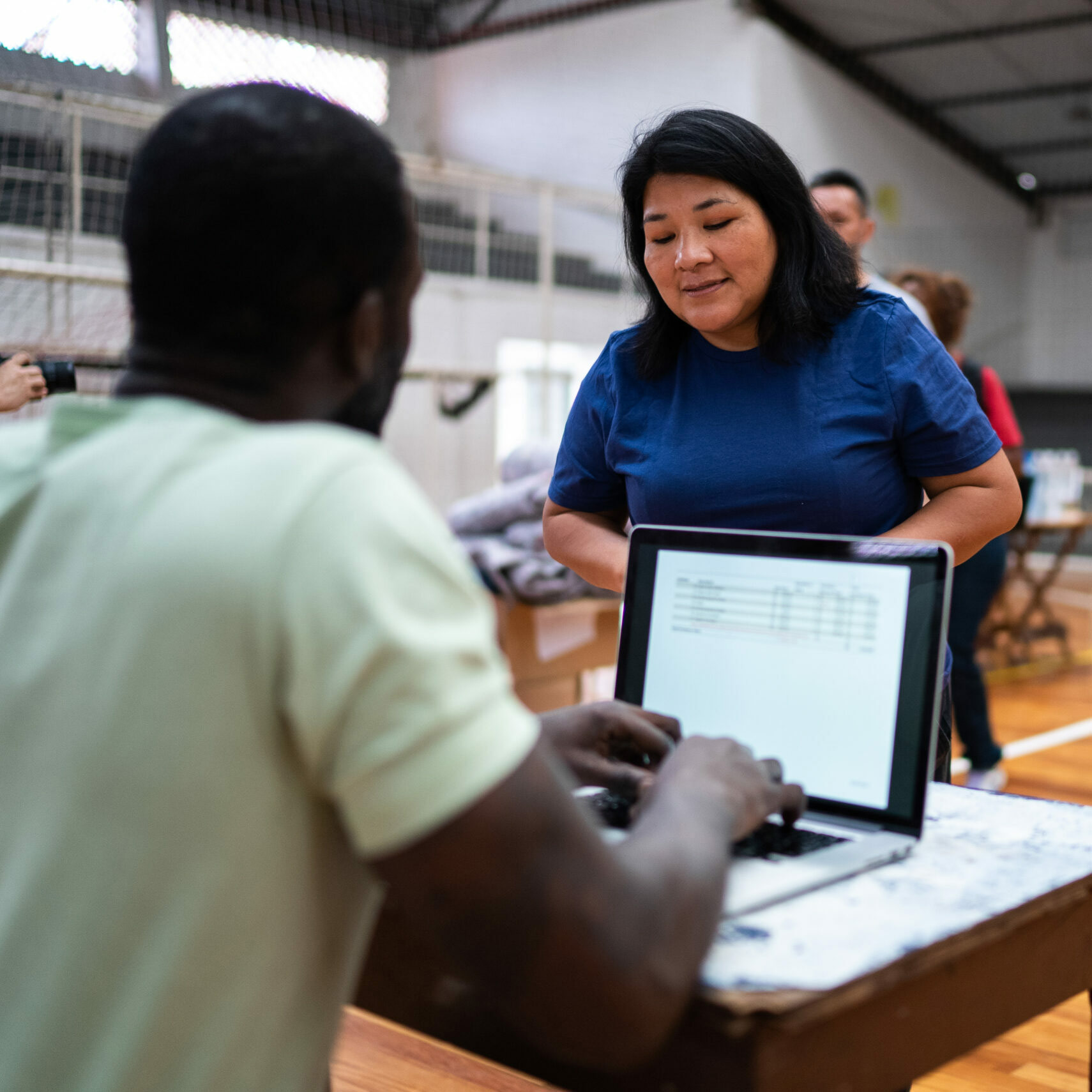 Volunteer talking with a refugee woman while using the laptop at a refugee sheltering